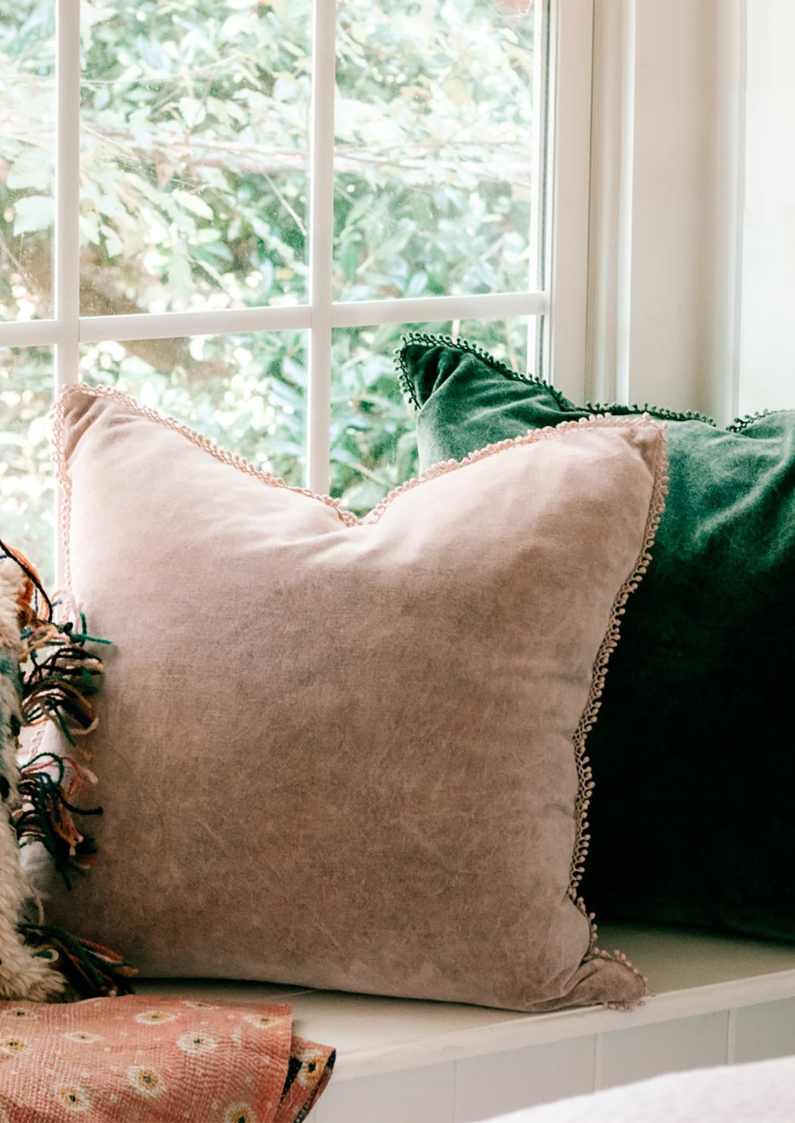 Pink and green velvet throw pillows on a window ledge.