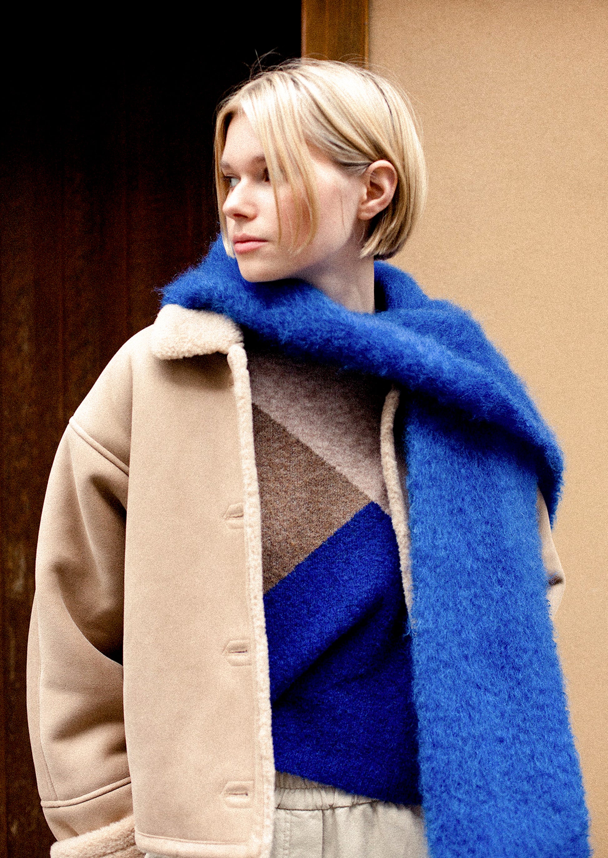 A woman wearing a fuzzy mohair scarf in cobalt blue.