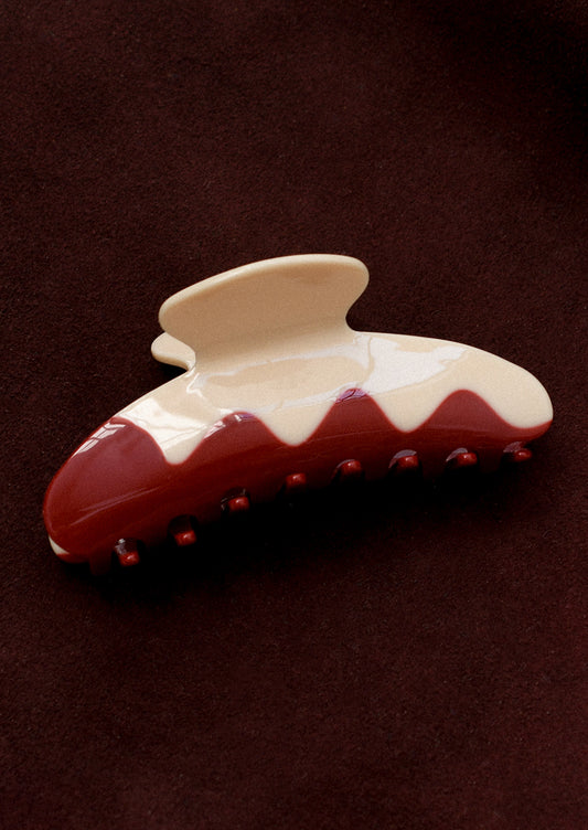 A hair claw in ivory with red squiggly wave pattern.