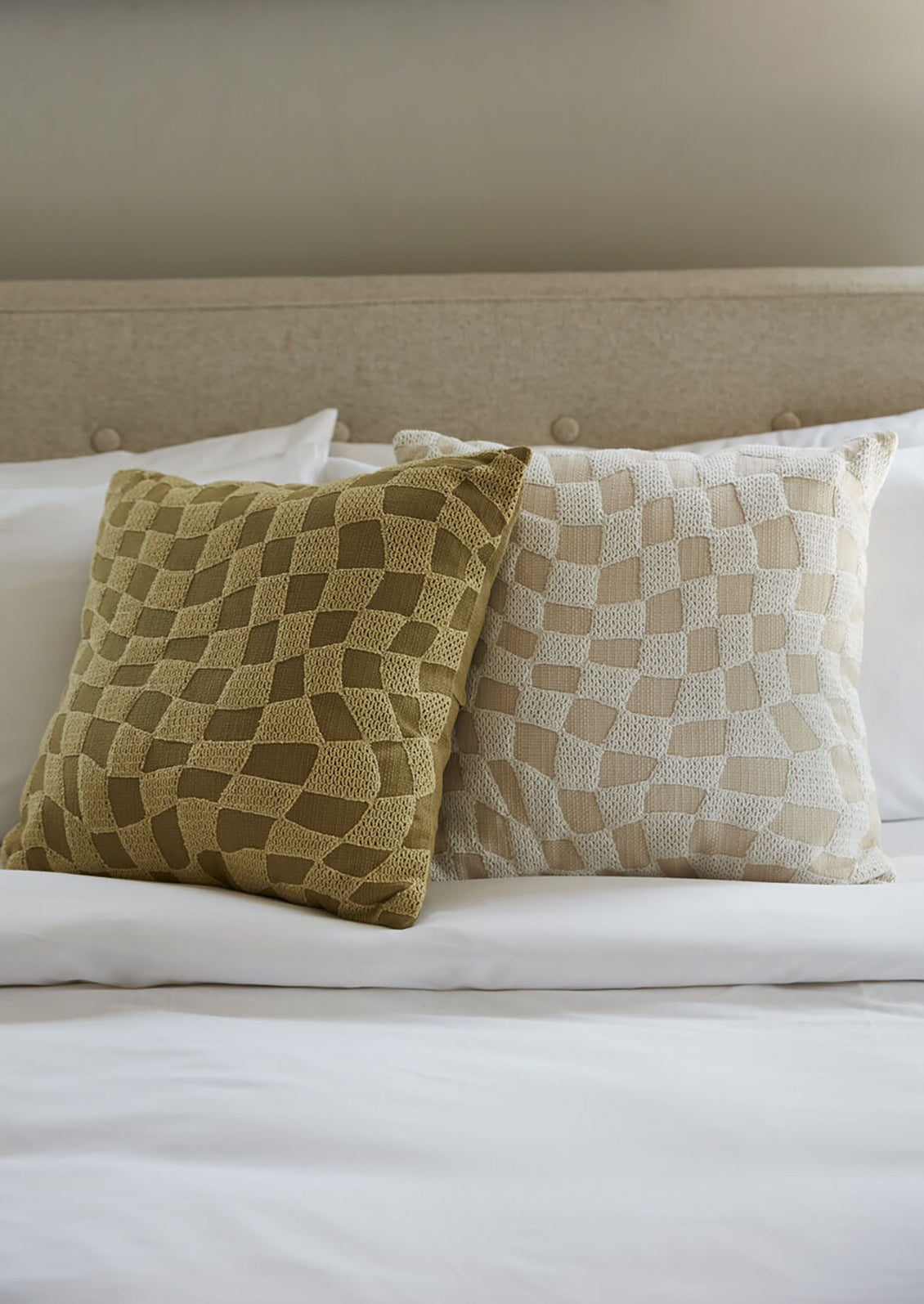 A throw pillow with embroidered tonal checker pattern.