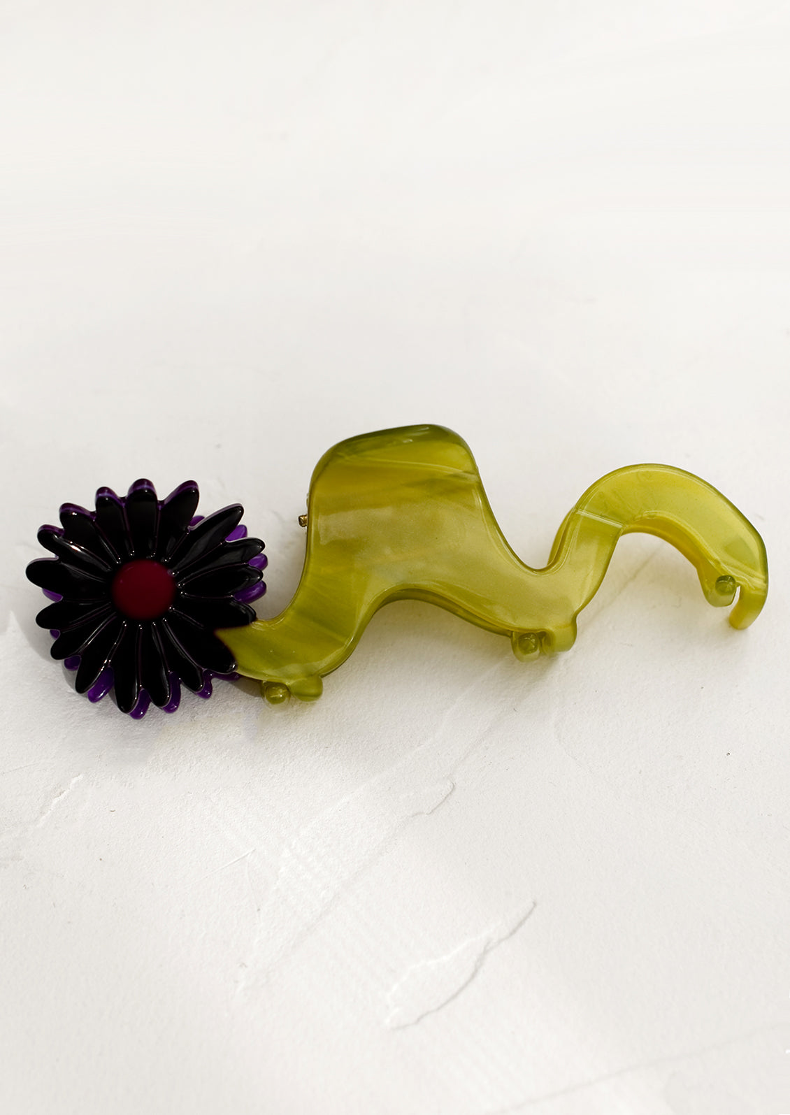 A wavy green hair claw with purple flower.