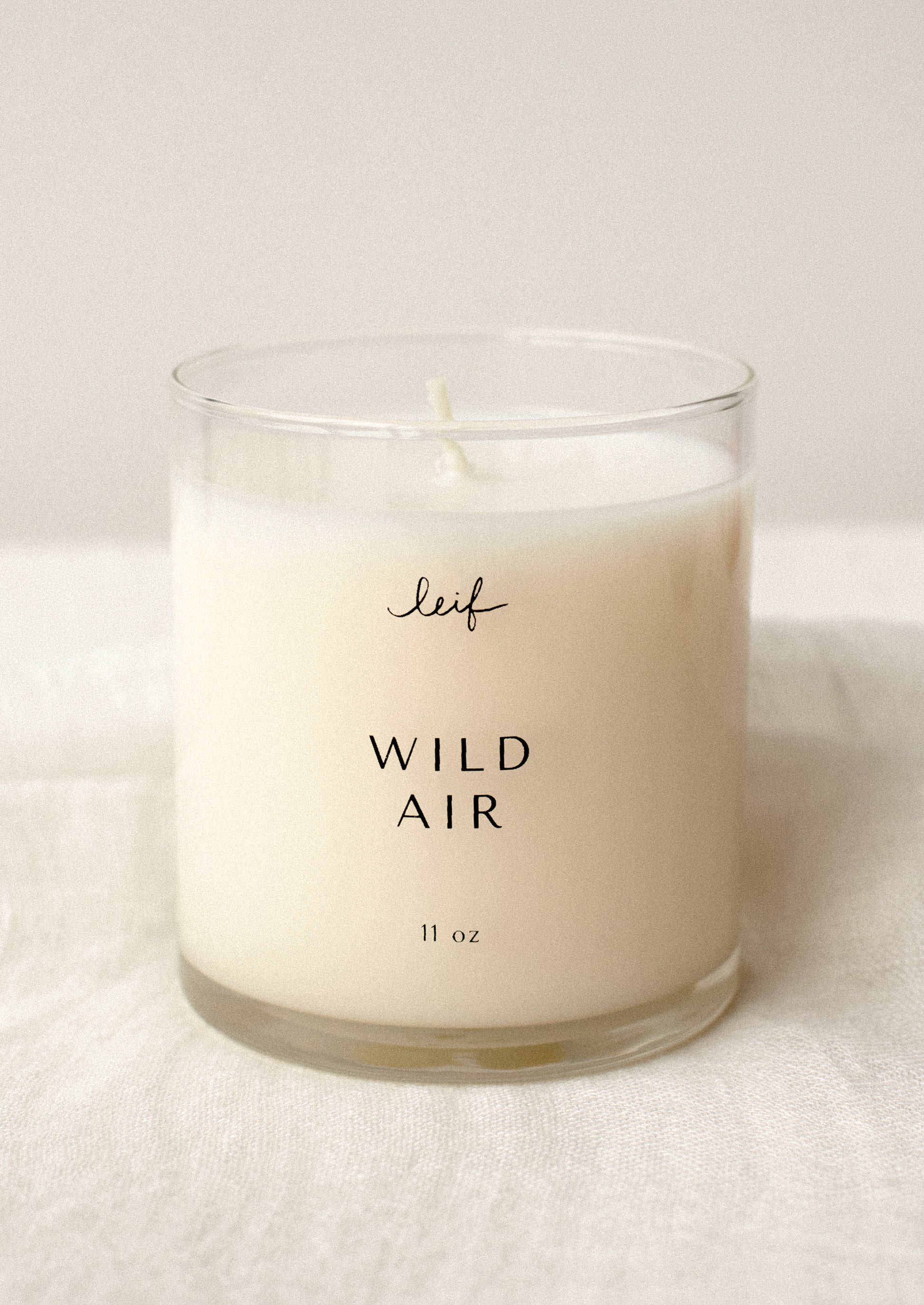 A candle in clear glass jar labeled "Wild Air".