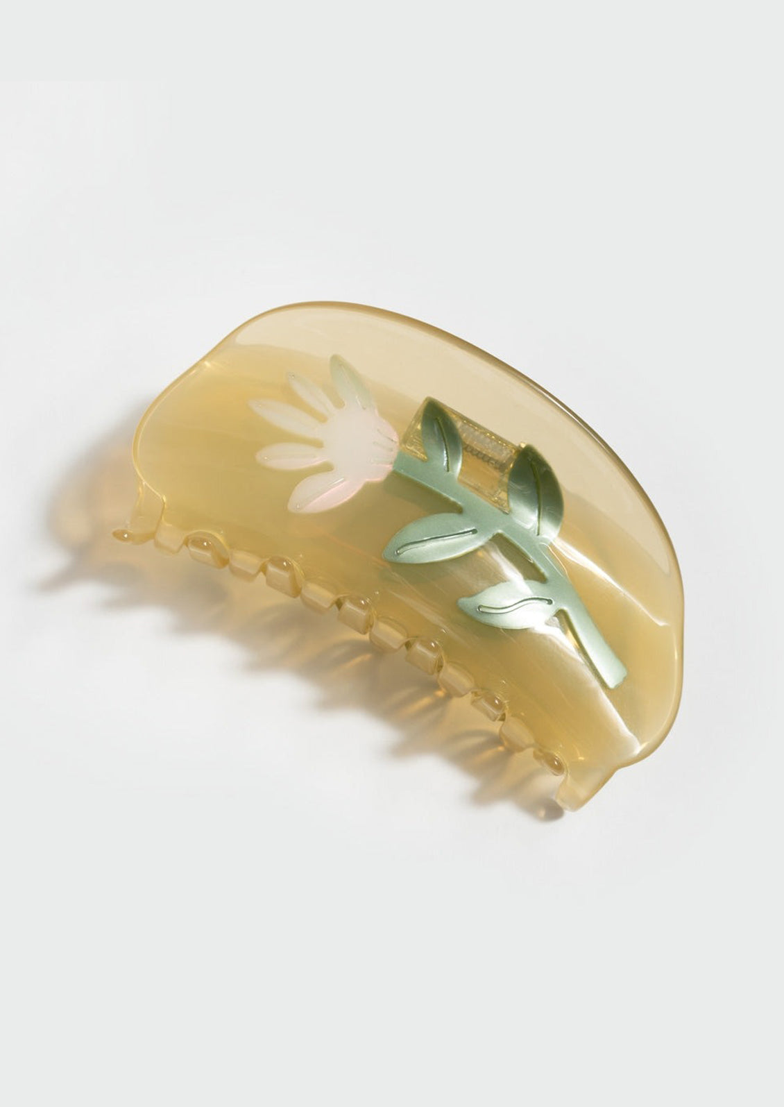 A transparent yellow curved shape hair claw with thistle design.