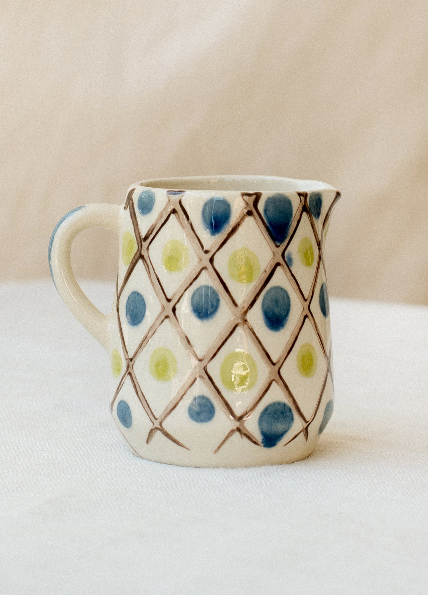 Small mini creamer pitcher in brown, blue and green diamond and dot design.