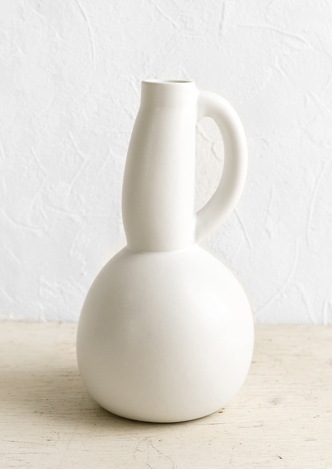 A white ceramic pitcher with curved, voluptuous silhouette.