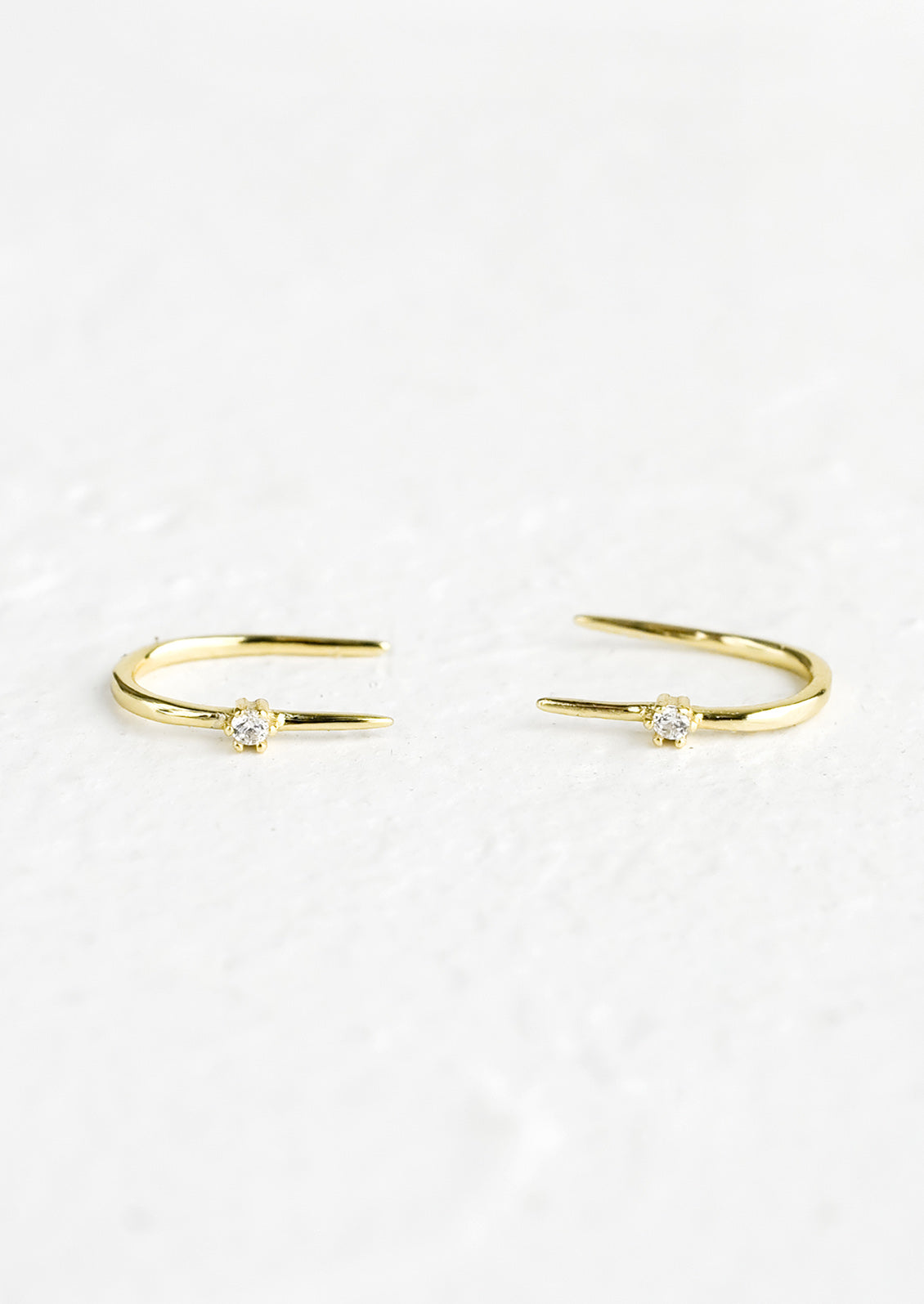 A pair of gold threader studs with single crystal detail.