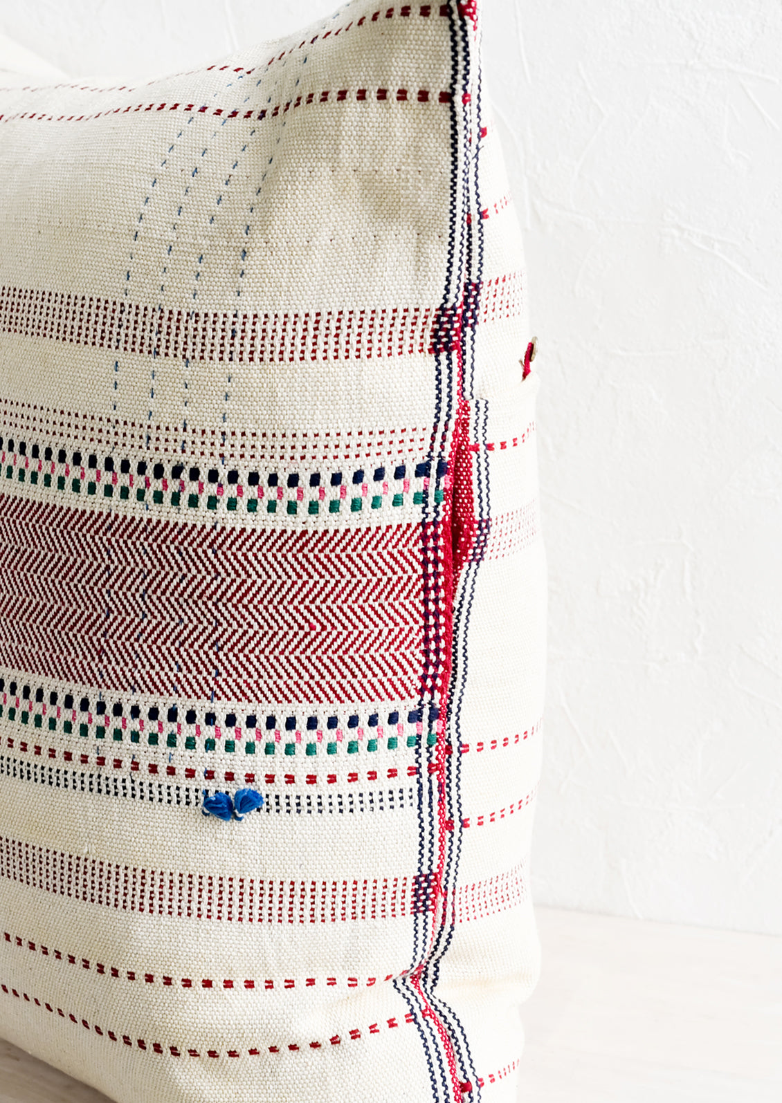 A double sided throw pillow with embroidery and tassel details.