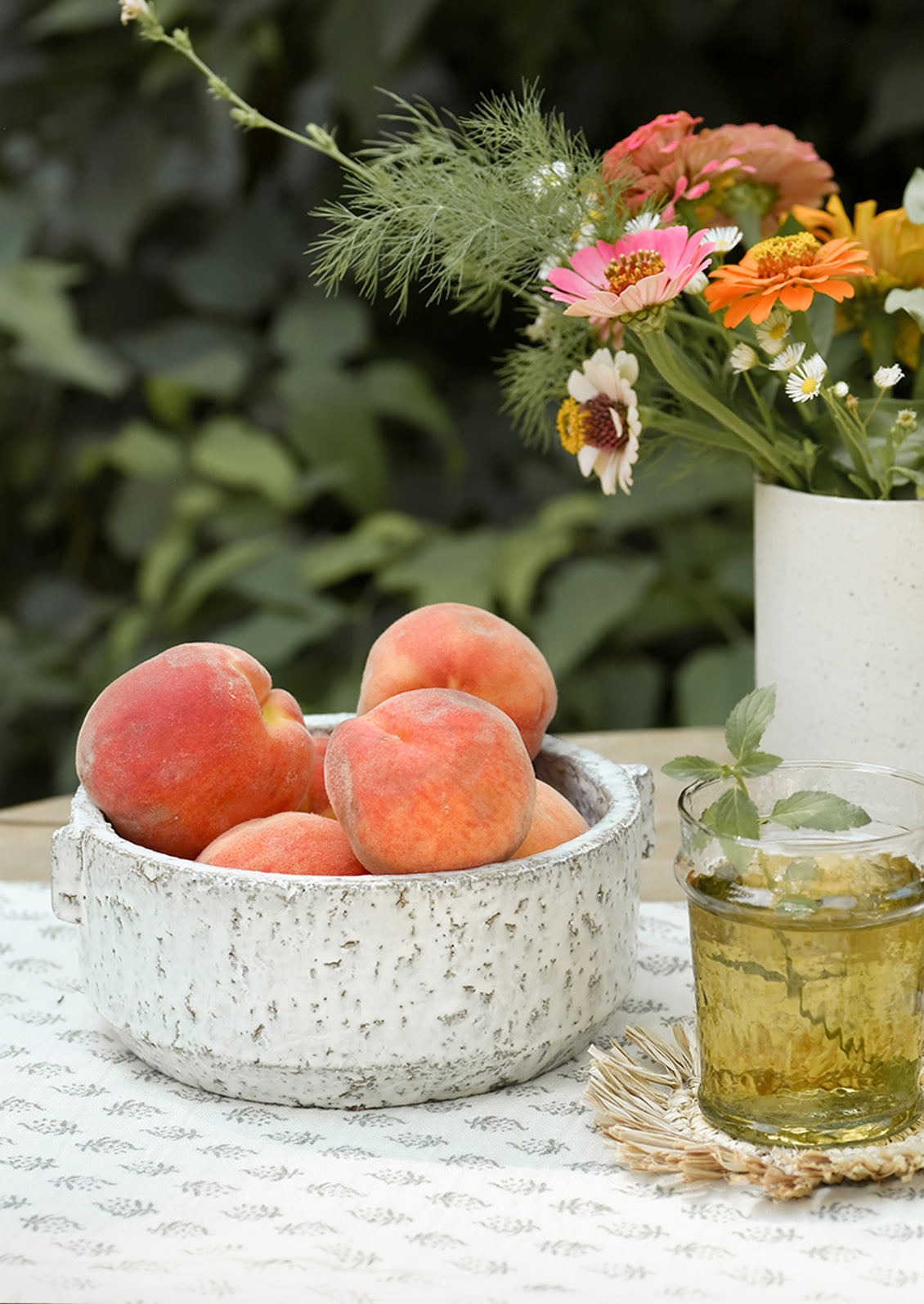 A textured ceramic bowl on a table, holding peaches.