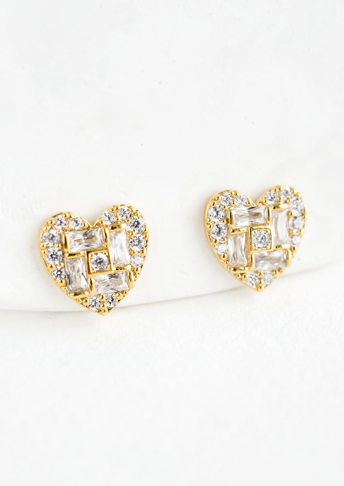 1: A pair of gold heart shaped stud earrings with a mix of rectangular and round crystal pave detailing.