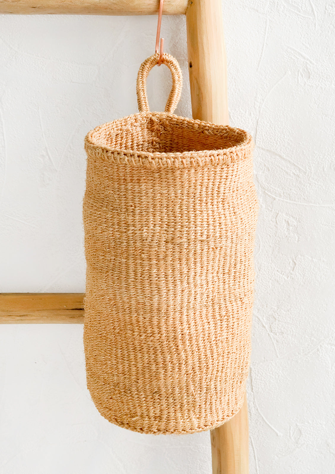 An oblong cylindrical basket woven from sisal in natural color.