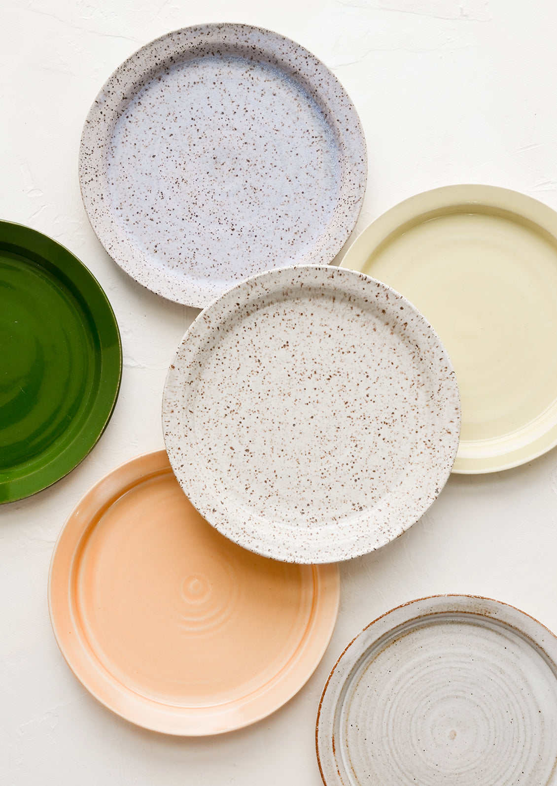 Assorted ceramic side plates in a mix of colors and glaze finishes.