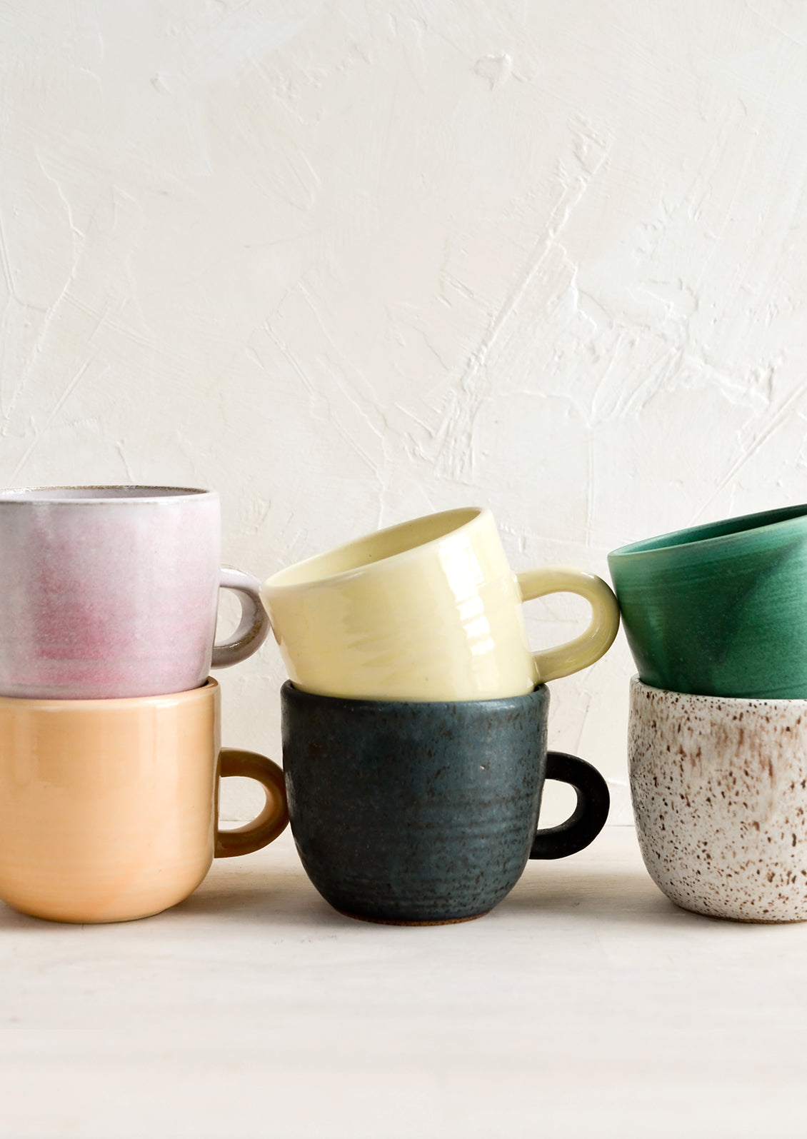 A stack of ceramic mugs in a mix of glazes and colors.