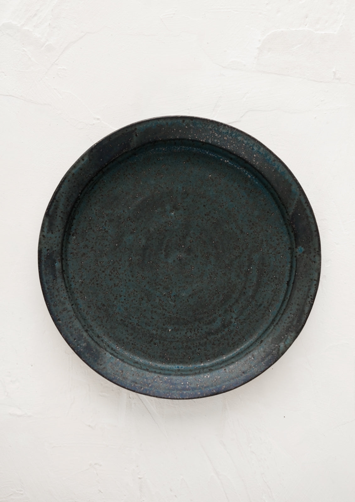 A ceramic side plate in matte deep blue speckle glaze.