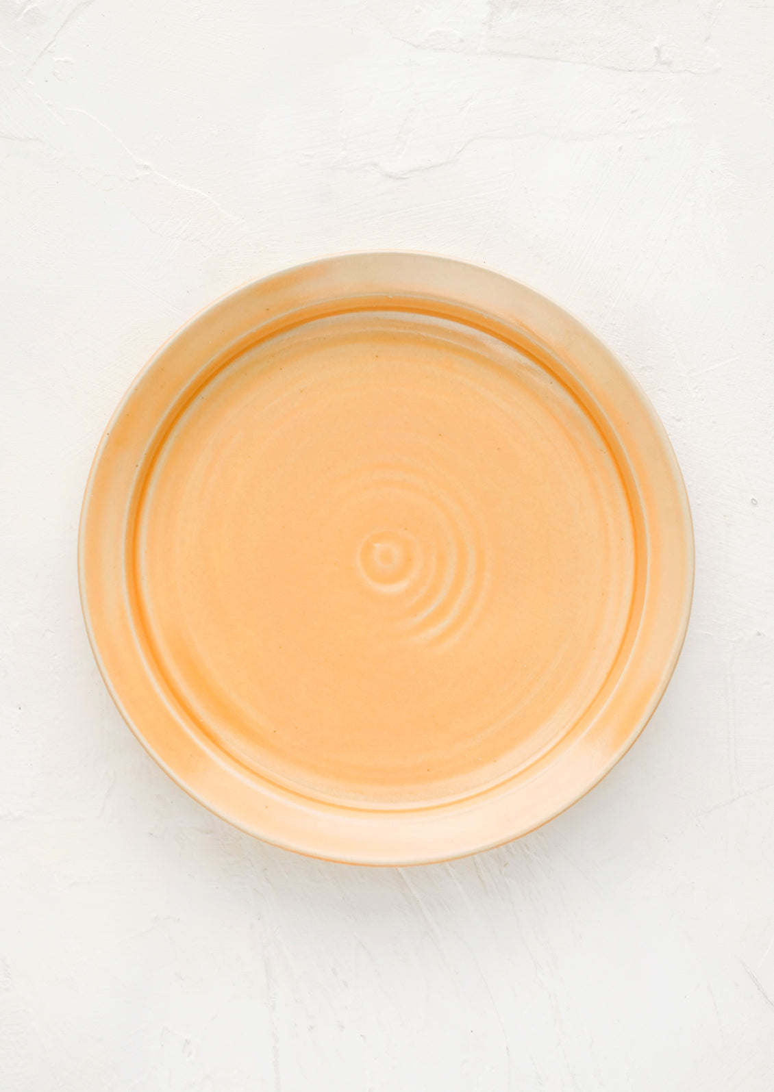 A ceramic side plate in glossy peach glaze.