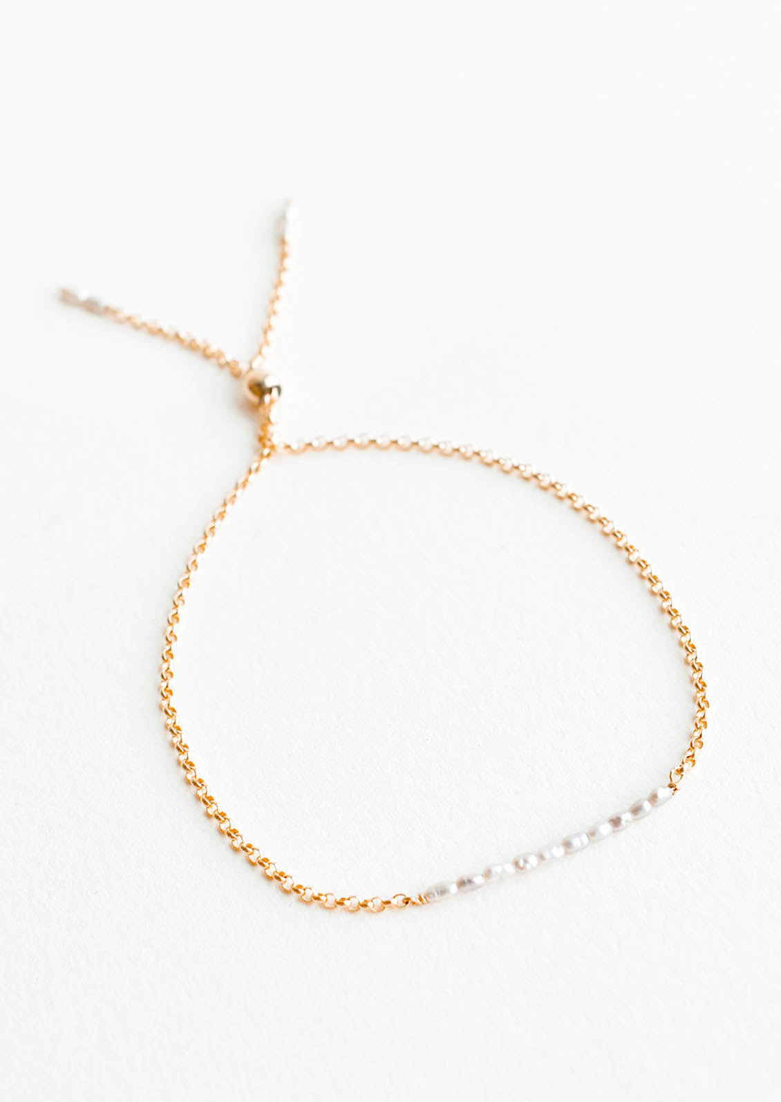 A delicate gold chain bracelet featuring a row of miniature freshwater pearls.