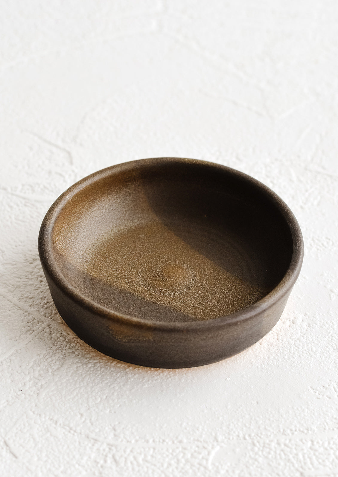 A small brown ceramic pinch bowl.