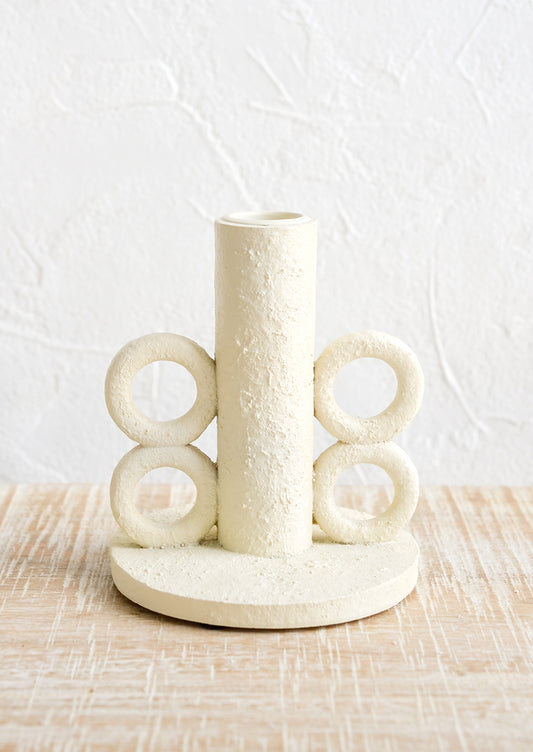 A taper candle holder in plaster finish with loop detailing at sides.