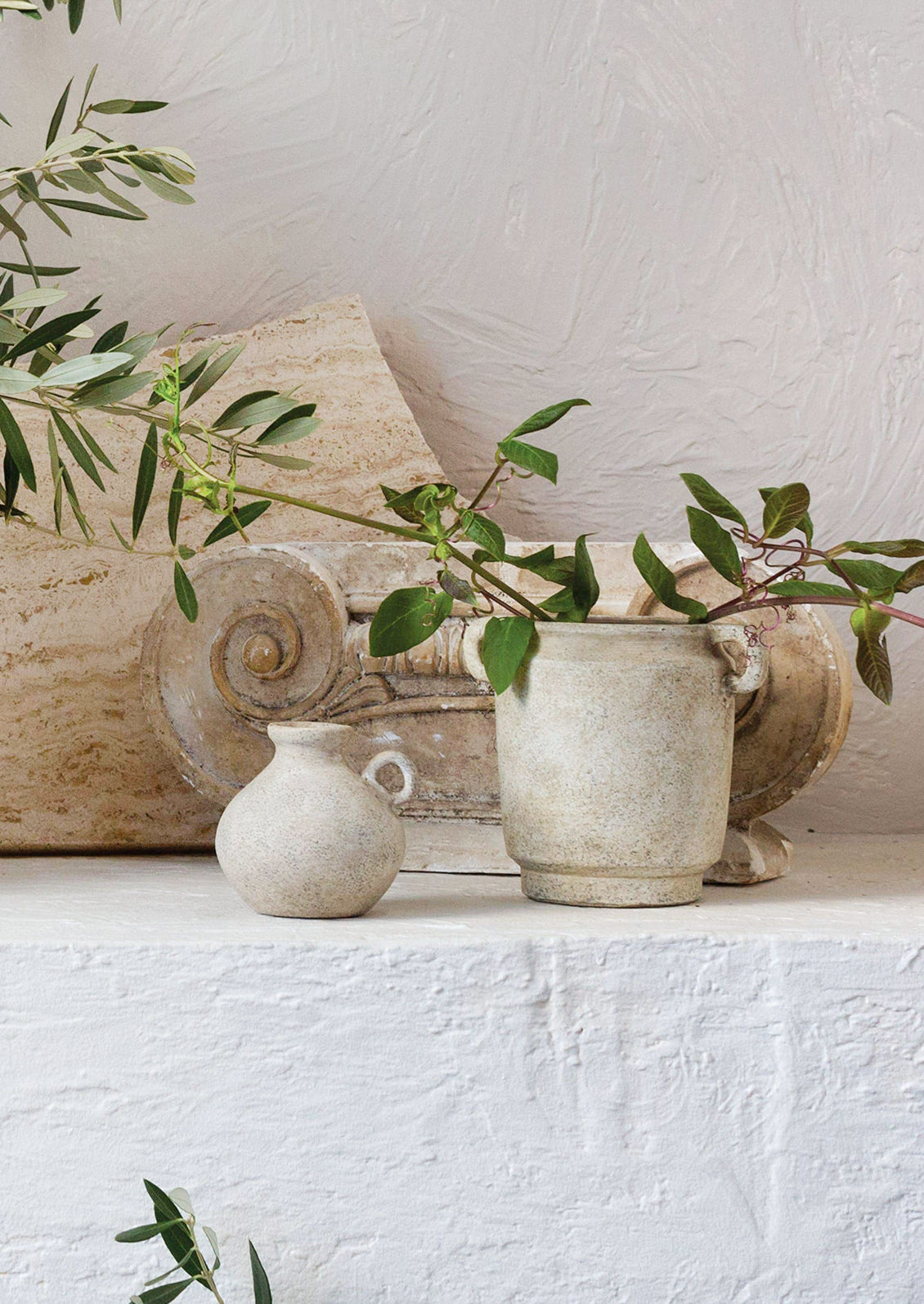 A distressed beige ceramic vase with handles at top sides.