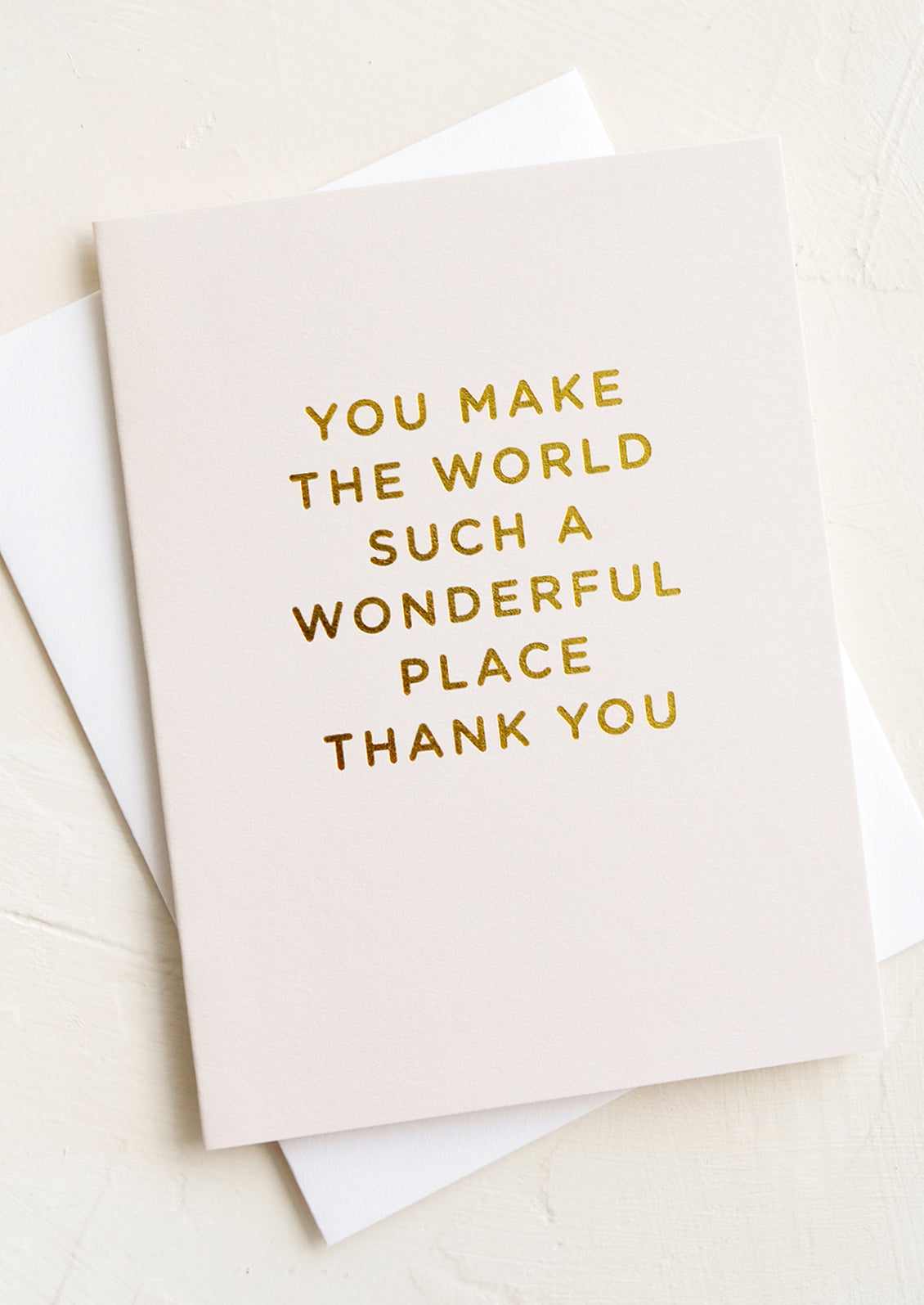 An ivory card with gold text reading "You make the world such a wonderful place thank you".