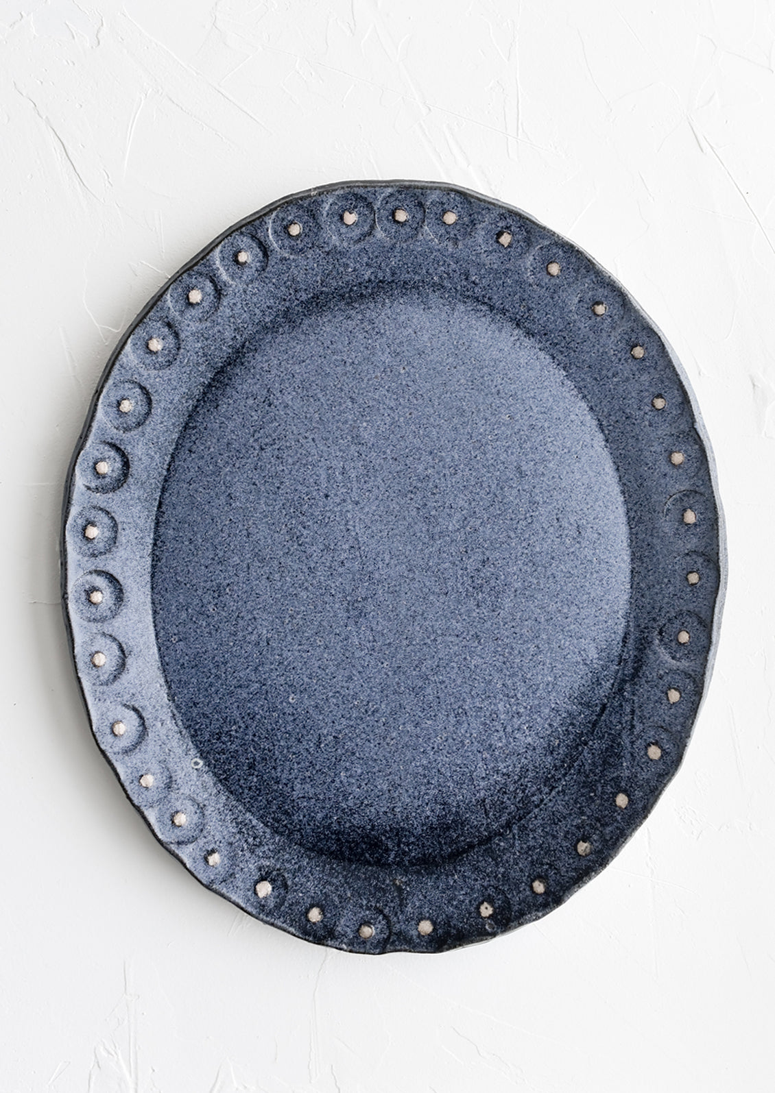 An oval shaped ceramic platter in steel blue with pink dot trim.