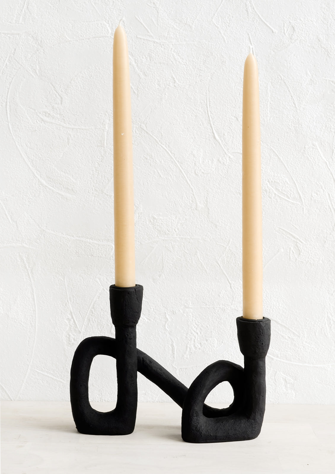 An asymmetrical taper holder in curved design, showing two taper candles.