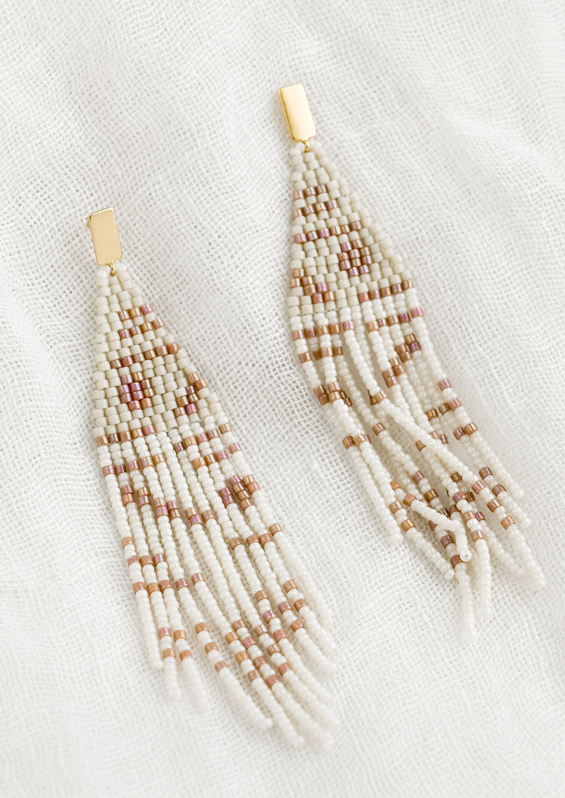 A pair of beaded earrings with geometric pattern in beige and white.