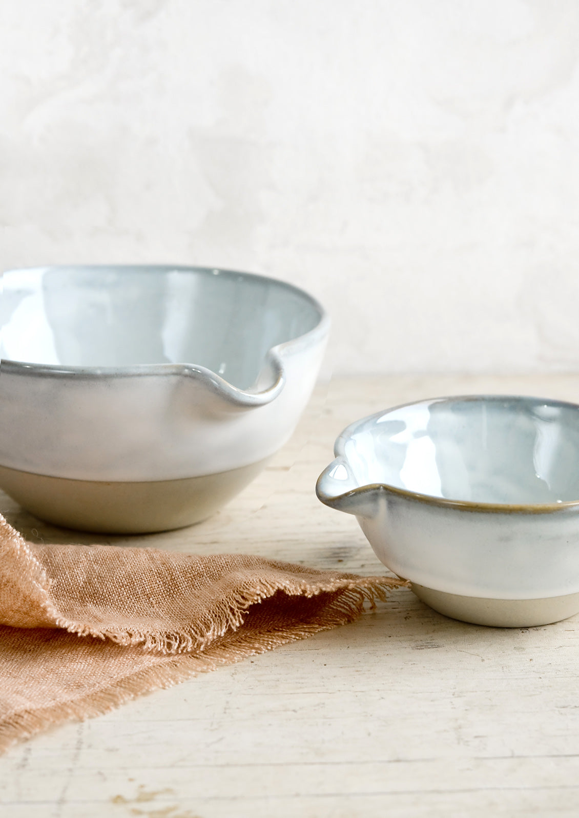 Two ceramic bowls with pouring spouts in large and small sizes.