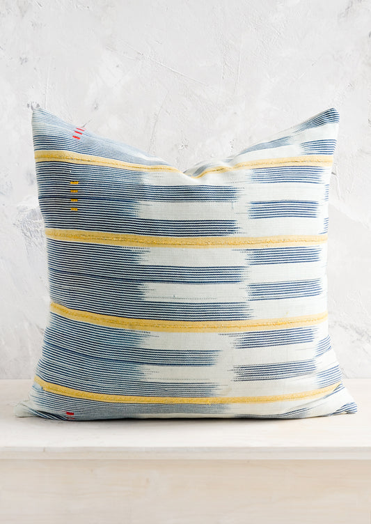 A square throw pillow in vintage African baule indigo ikat fabric with yellow accents.