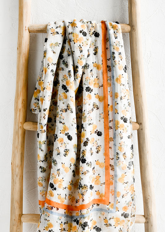 A floral print scarf with orange and blue border.