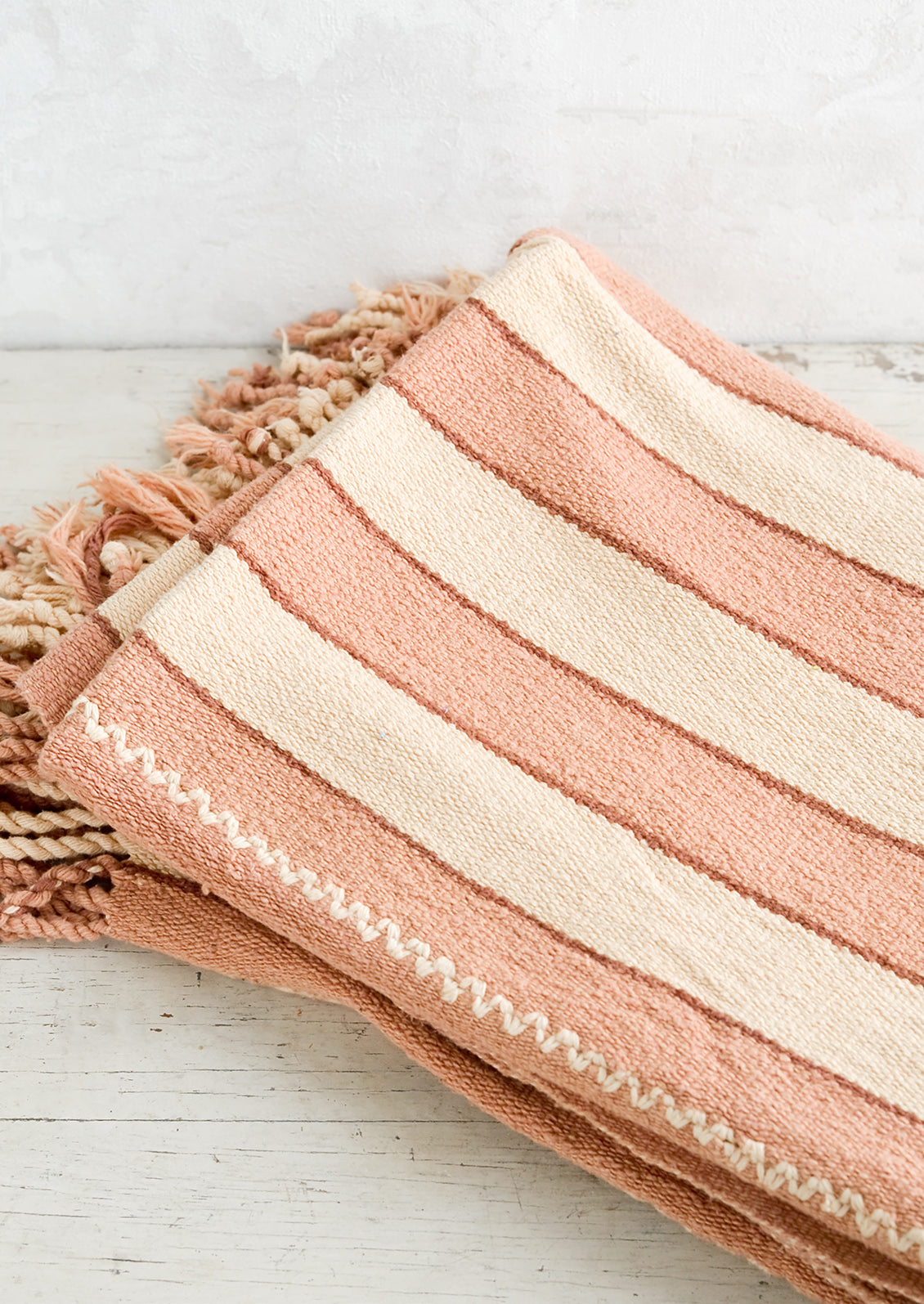 Natural woven cotton throw in blush and cream stripes with twisted fringe edge