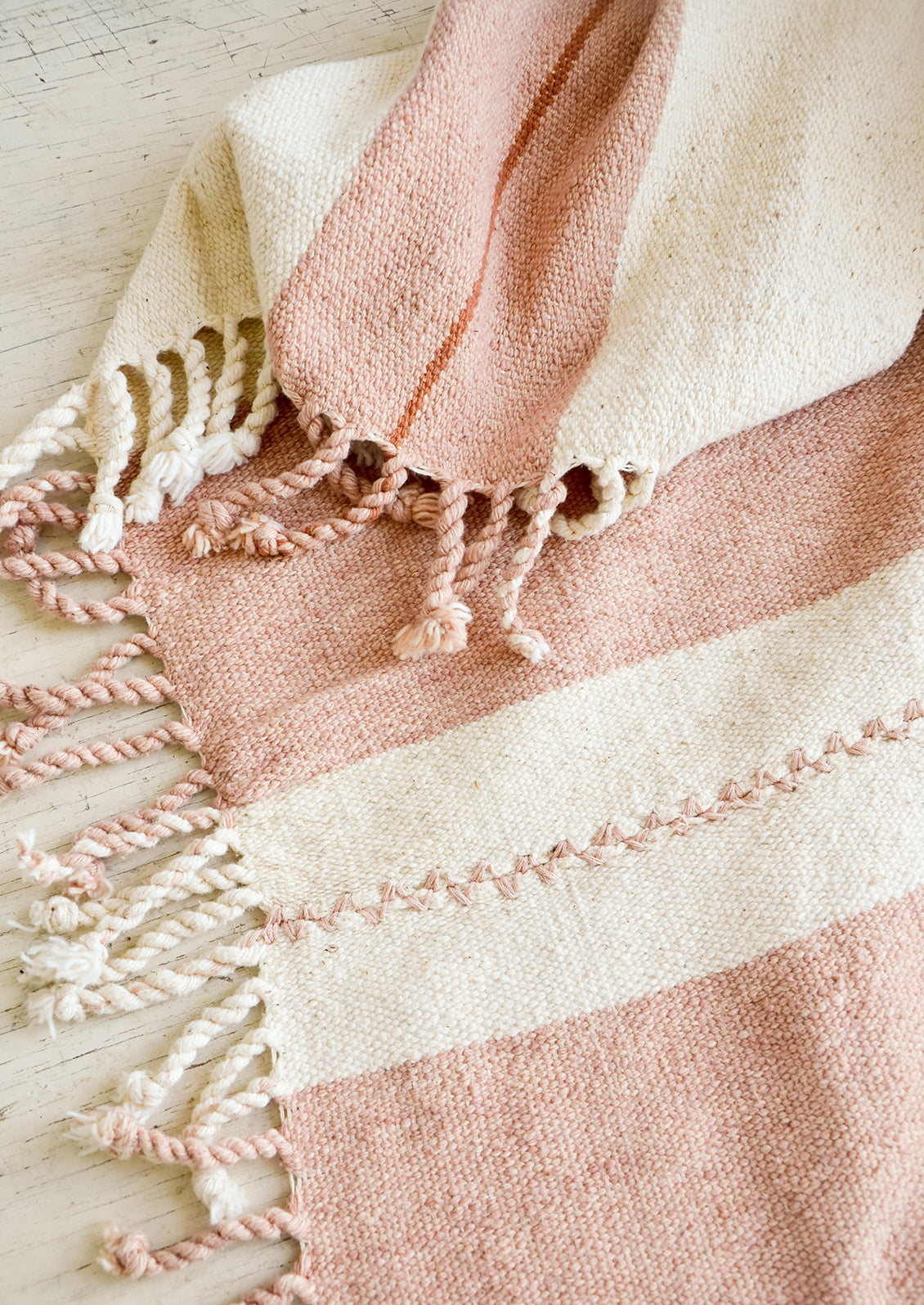 Natural woven cotton throw in blush and terracotta stripes with twisted fringe edge