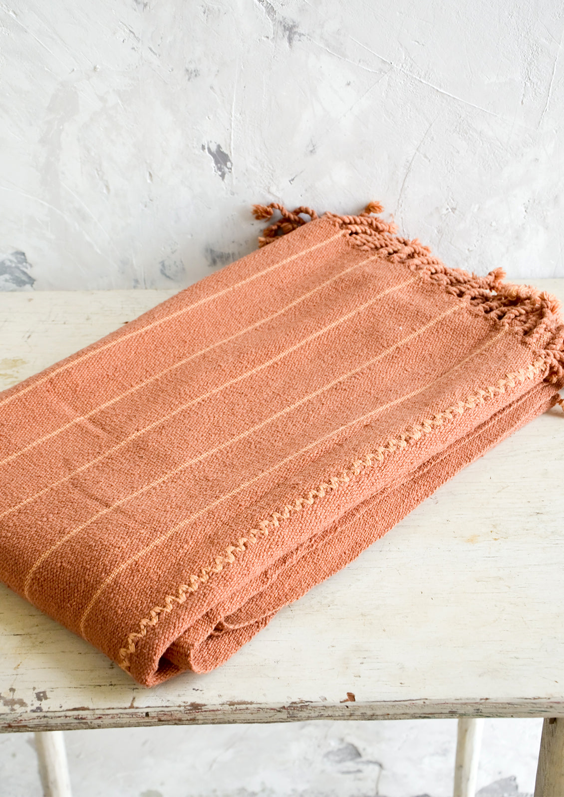 Natural woven cotton throw in peach and terracotta stripes with twisted fringe edge