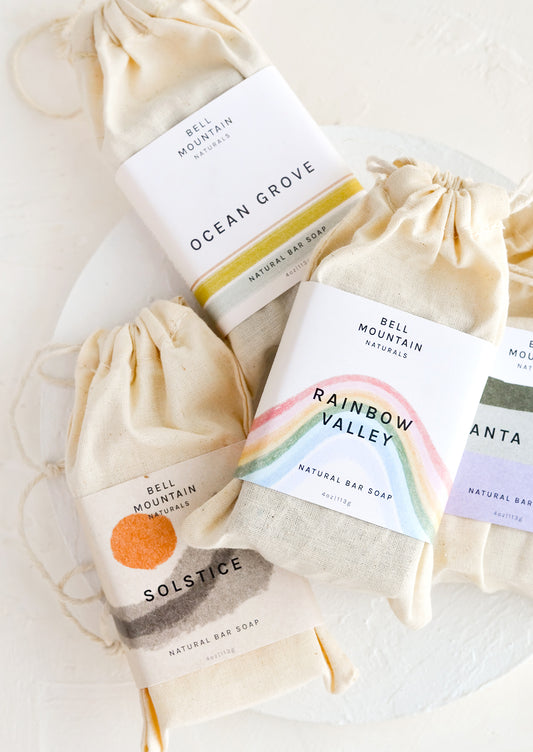 A stack of bar soaps in labeled muslin pouches.