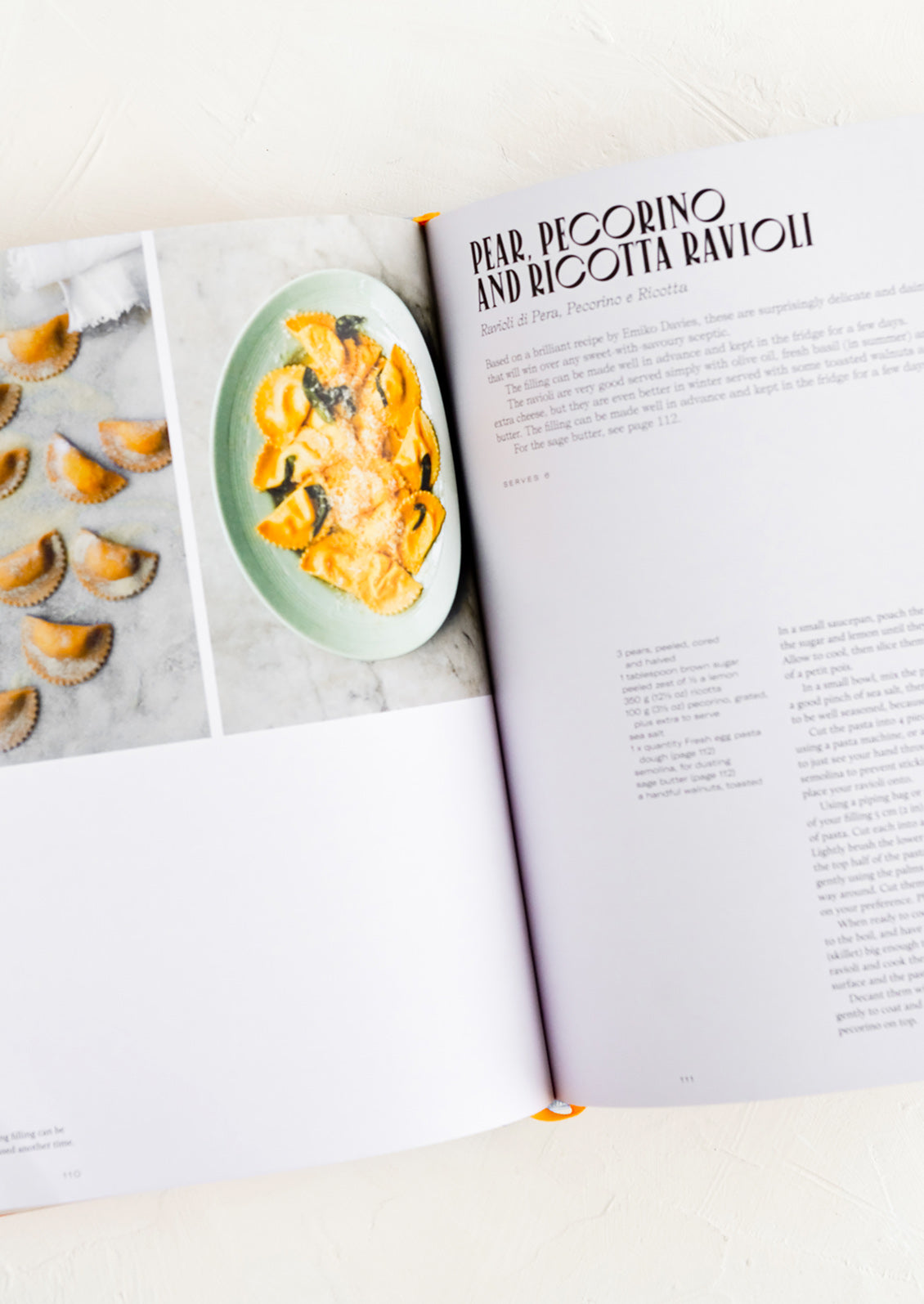 A hardcover cookbook open to a page with a recipe for ravioli.