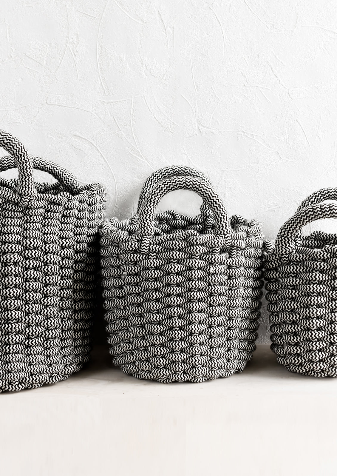 Black and white woven rope baskets in three incremental sizes.