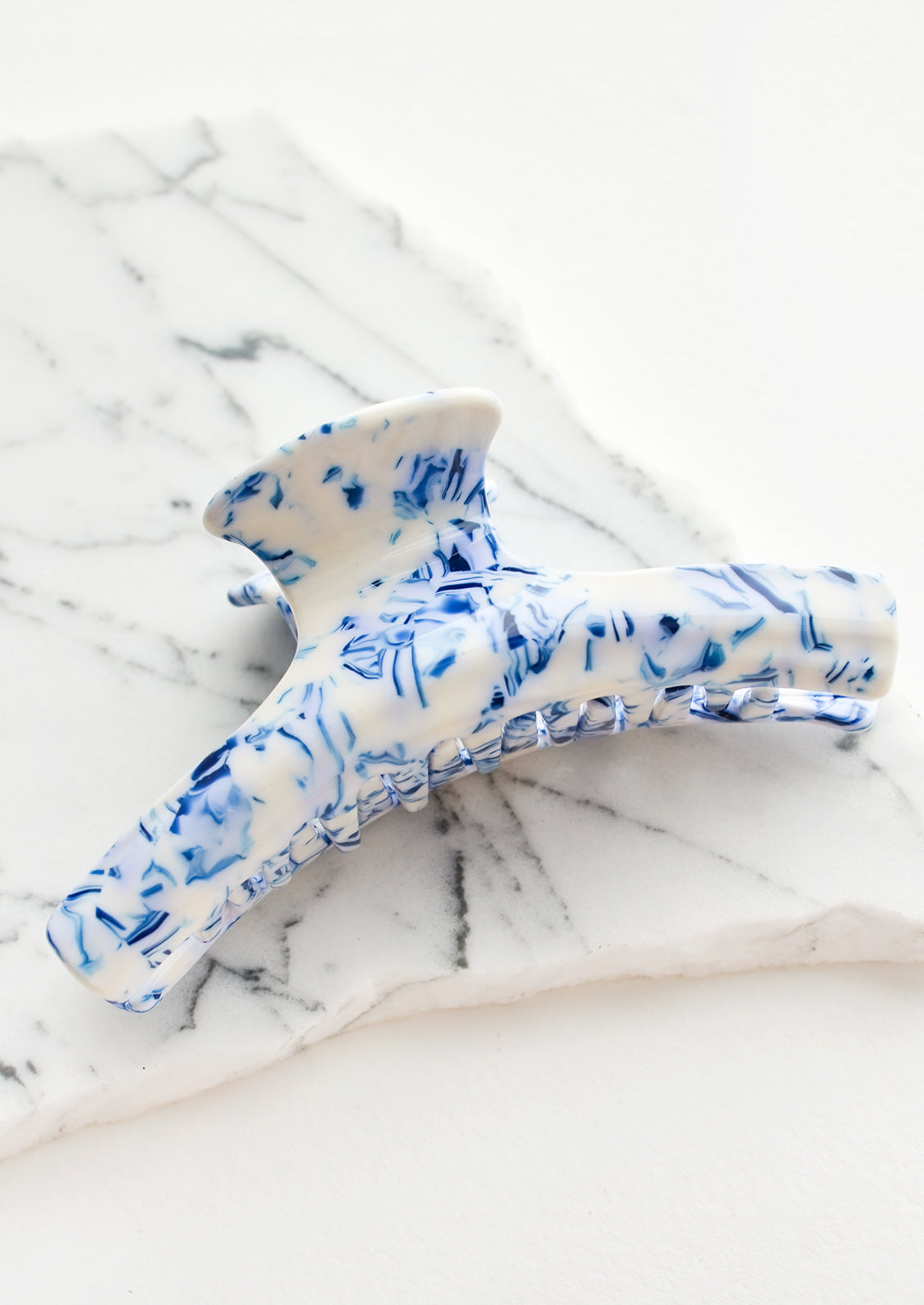 A hinged hair claw in marbled blue and white acetate.