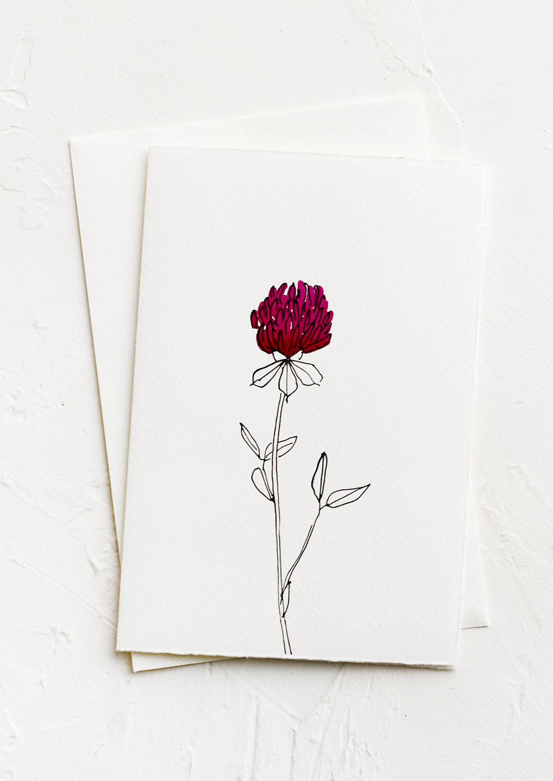 A white greeting card with a hand painted illustration of a red clover flower.