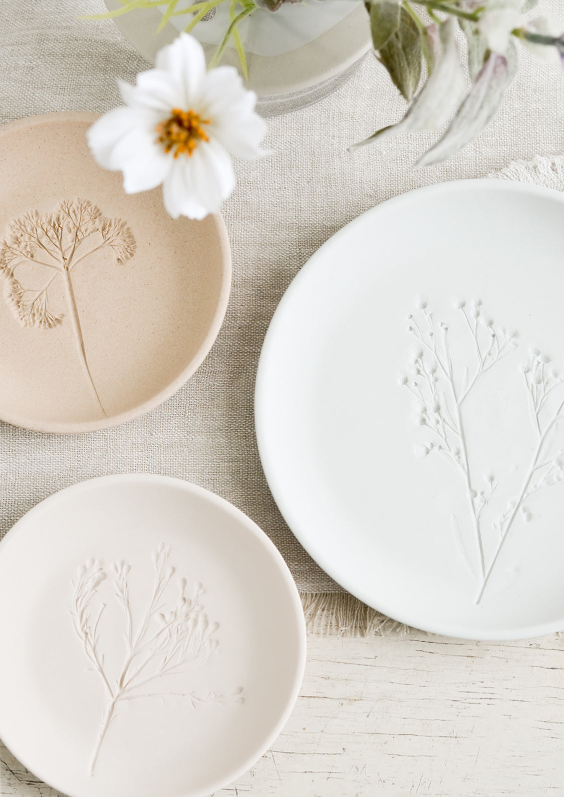 Stacked pastel porcelain plates with plant imprint designs.