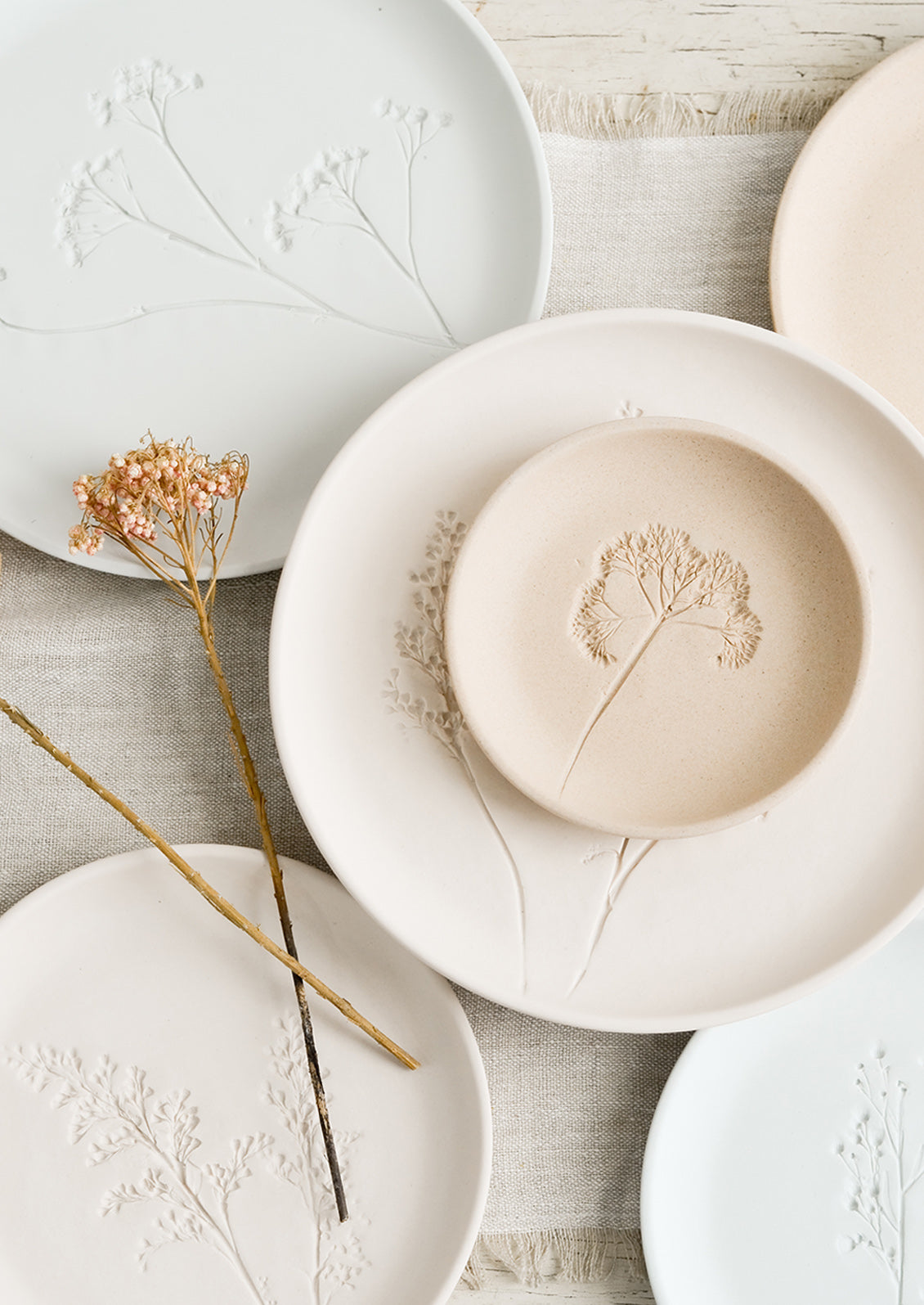 Stacked pastel porcelain plates with plant imprint designs.