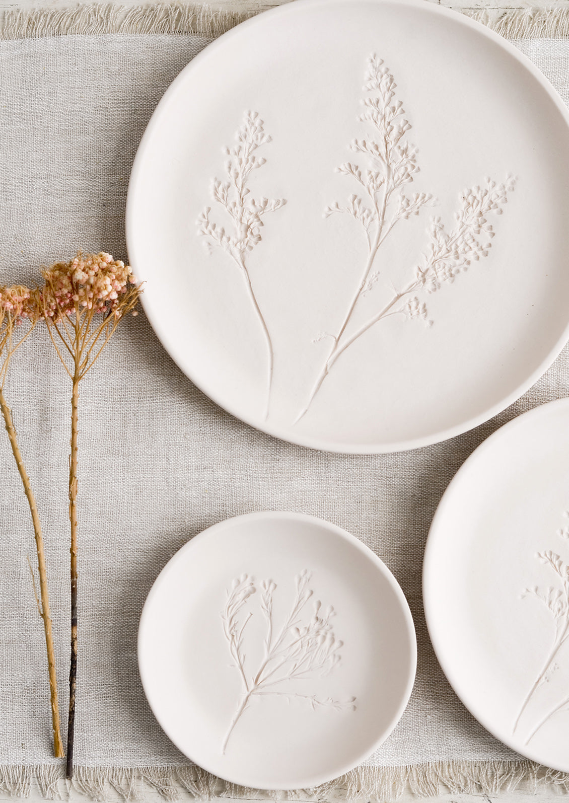 Stacked pastel porcelain plates with plant imprint designs.