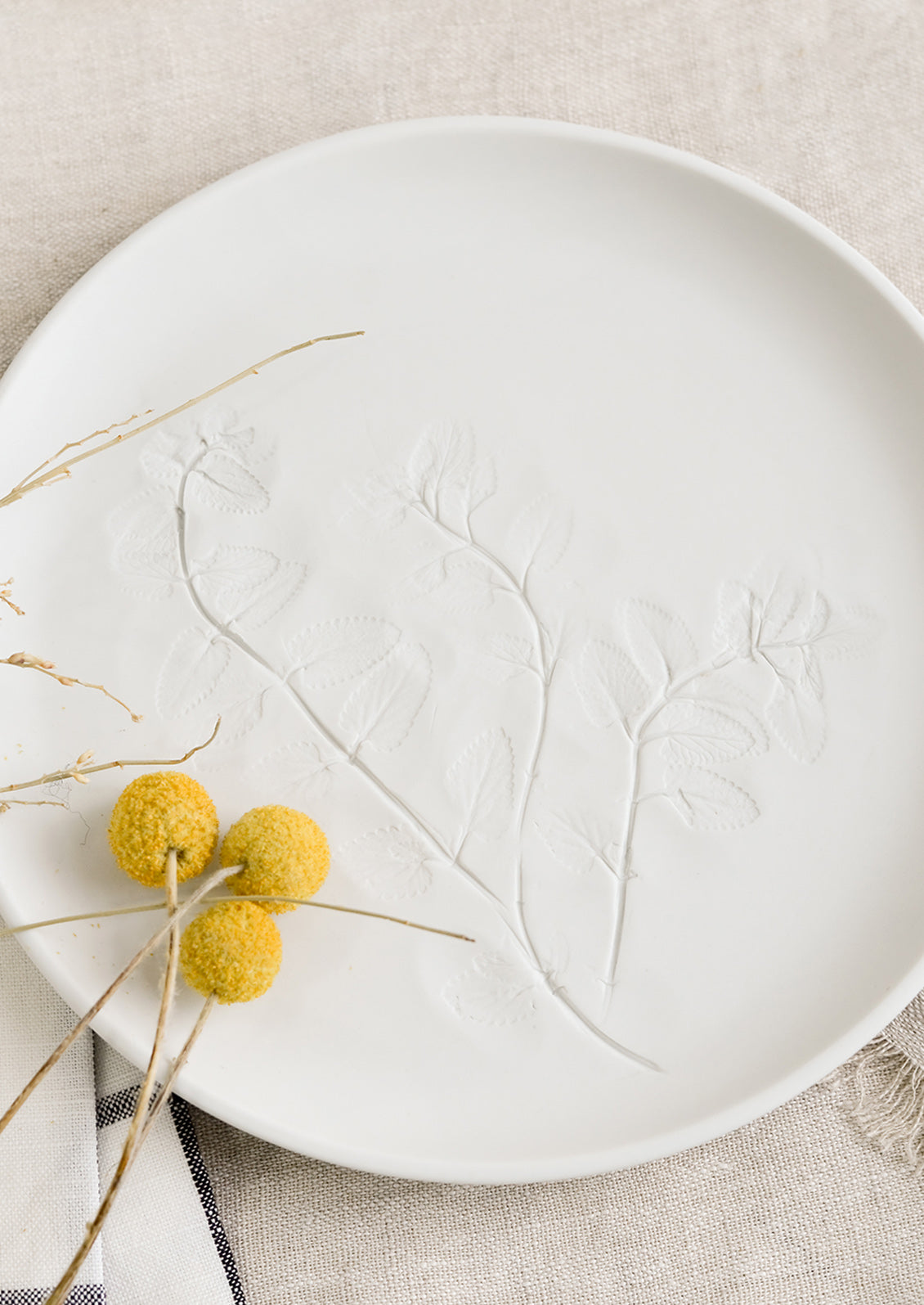 A white porcelain plate with impression of mint leaves.