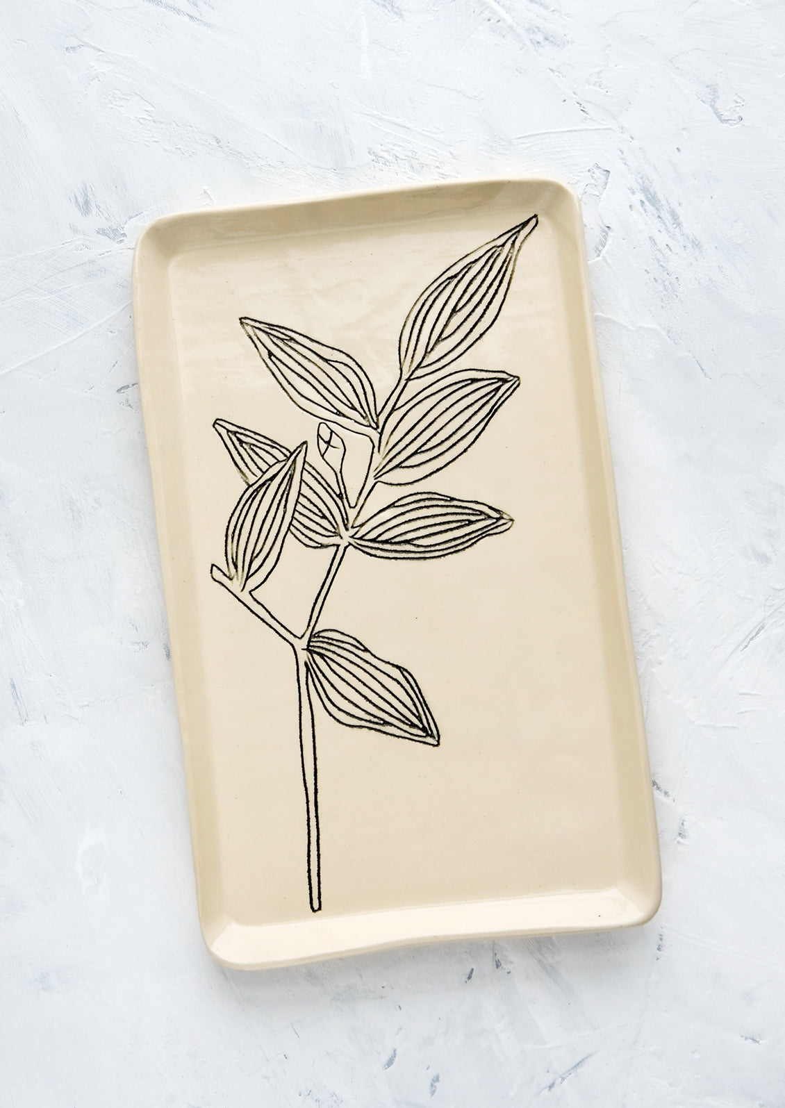 A rectangular ceramic tray in natural bisque color with an etched black drawing of Bellwort plant.