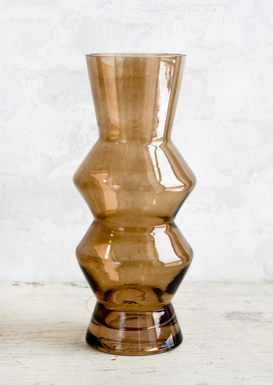 A tall glass vase in brown glass with zig zag silhouette.