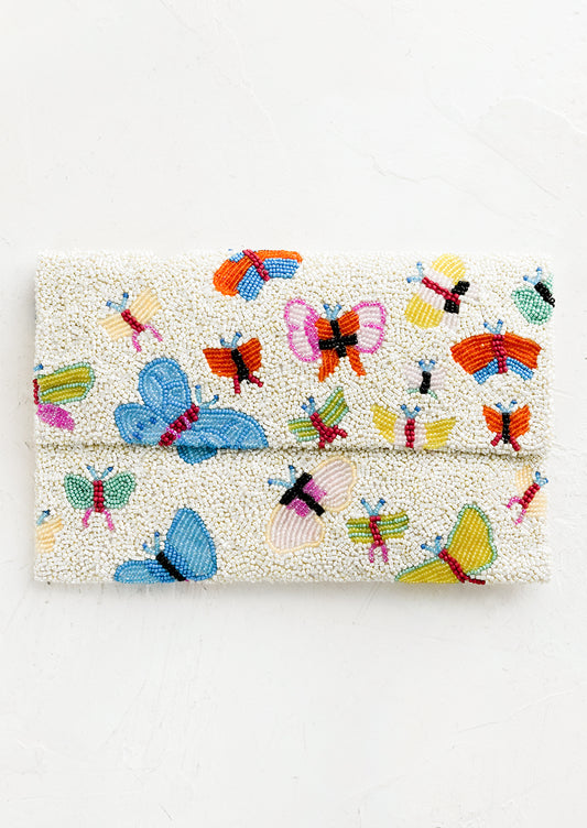 A white beaded clutch with front foldover flap, with multicolor butterfly design.