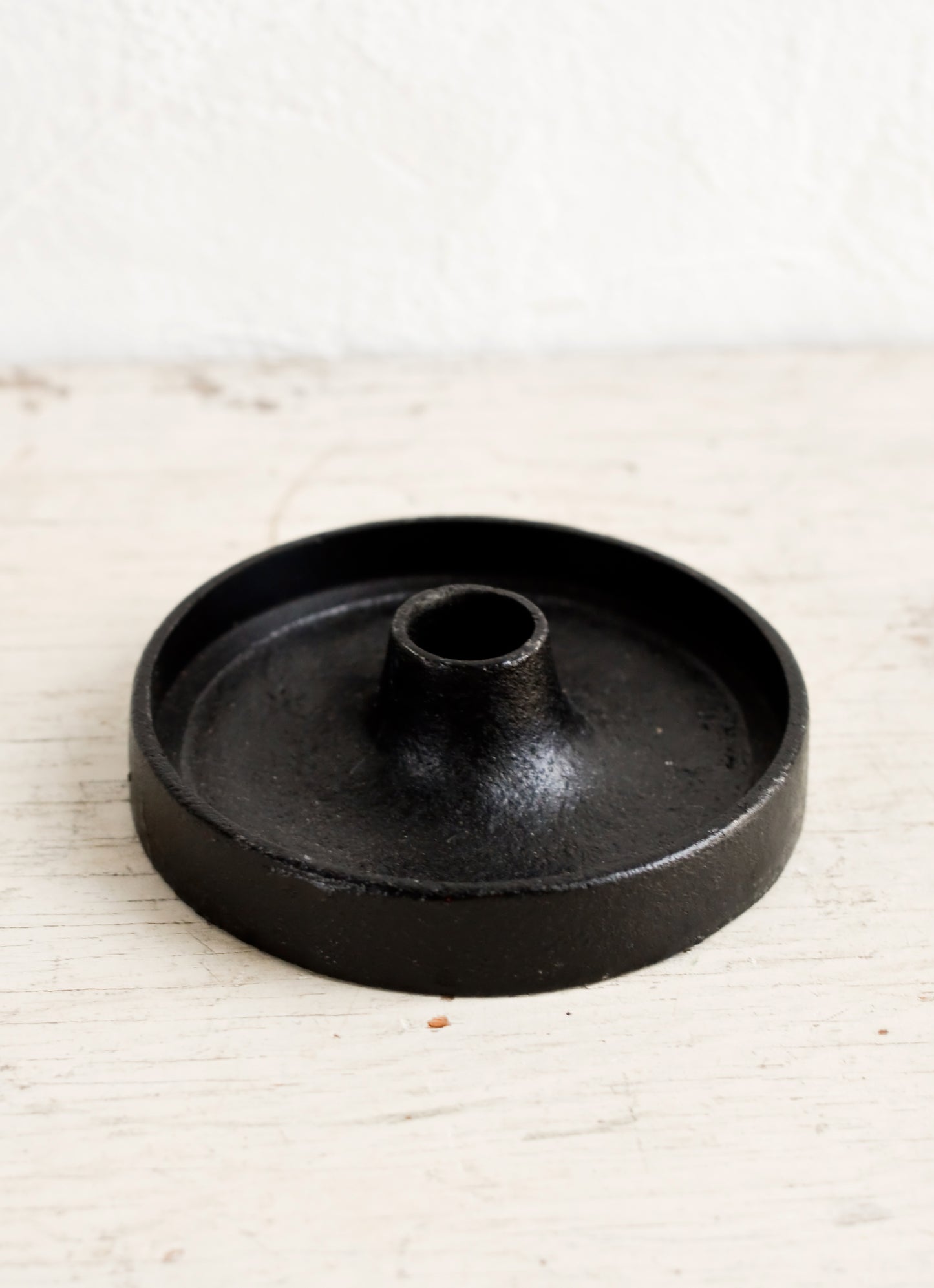 A taper candle holder in black cast iron with a wide base.