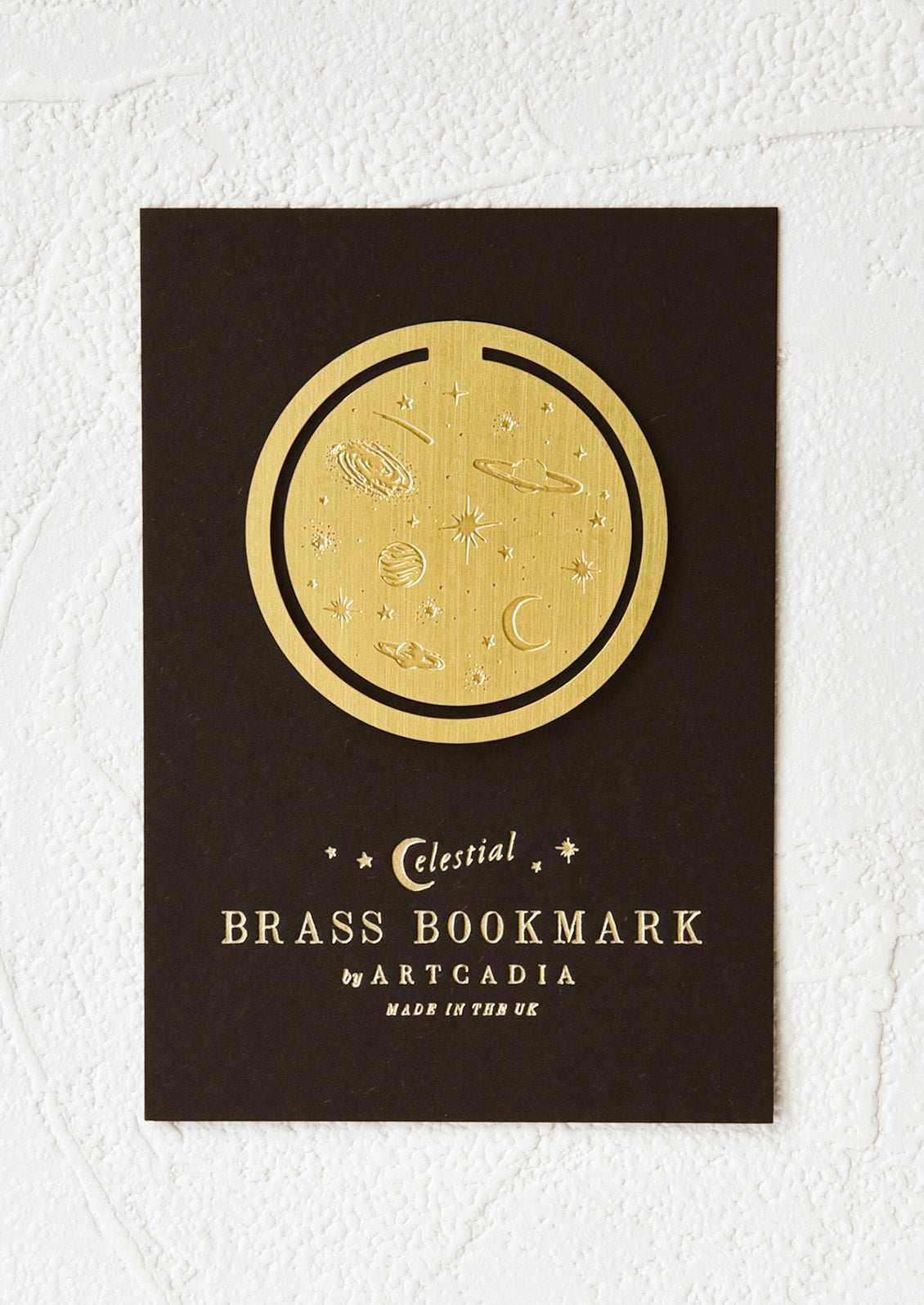 A circular brass bookmark with etched celestial pattern.