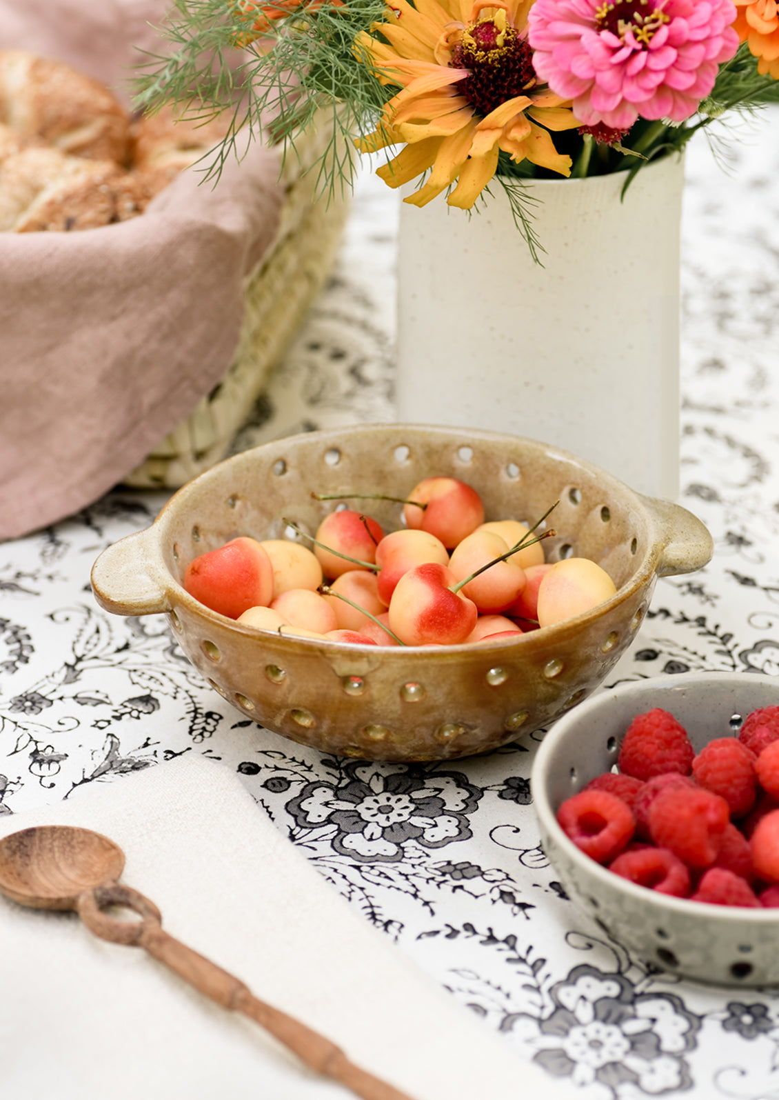 A berry bowl colander with cherries.