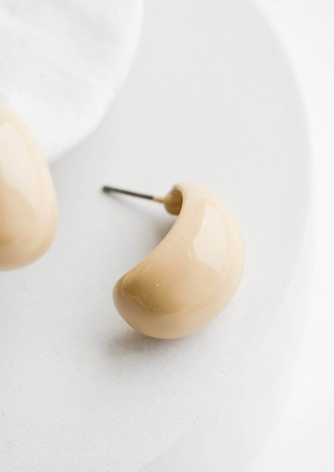 A pair of glossy ivory bean shaped earrings.