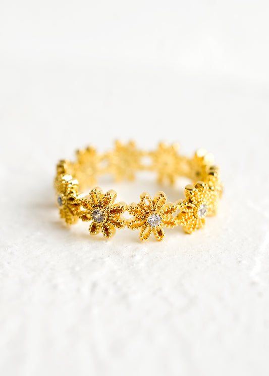 A gold ring made of flower shapes with crystal centers.