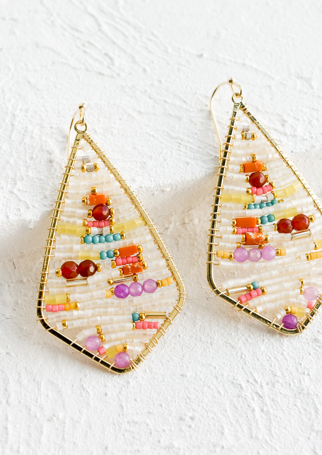 A pair of beaded earrings in teardrop frame.